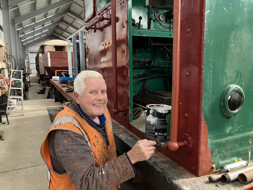 Ron Jones applying purple-red enamel finishing coat to the side of the cab 